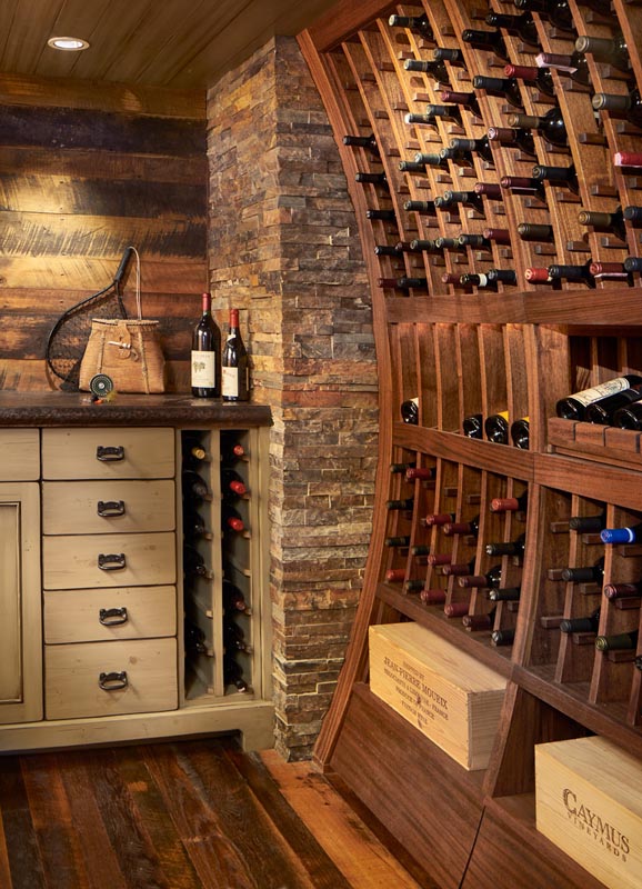 A cozy wine cellar featuring a curved wooden rack filled with wine bottles, a stone column, and a wooden cabinet with drawers. vintage elements and ambient lighting enhance the rustic charm.